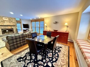 Ein Wohnzimmer mit Kamin, einem Essbereich mit Tisch und Stühlen, einer Couch und einem Fernseher.