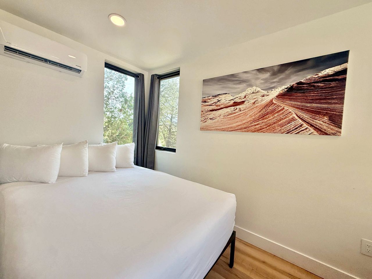 A bedroom with a large bed, a window, and a wall-mounted air conditioner.