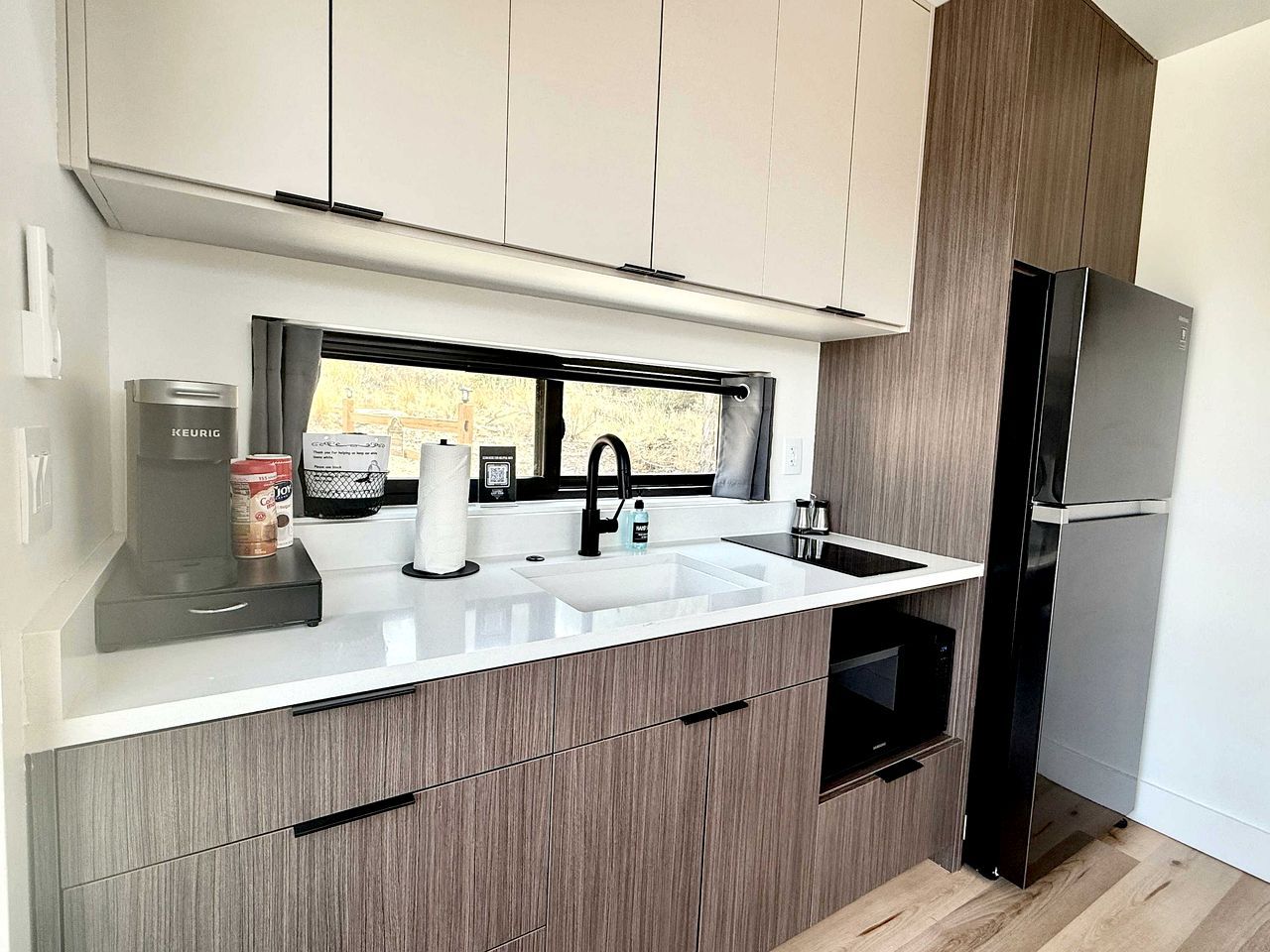 A modern kitchen with a built-in sink, a coffee maker, and a refrigerator.
