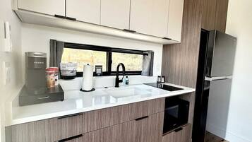 A modern kitchen with a built-in sink, a coffee maker, and a refrigerator.