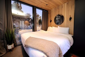 A modern bedroom with a large bed, a circular mirror, and a view of the outdoors. - Chic Tiny House with Outdoor Espace to Relax in Orderville, Utah (Orderville)