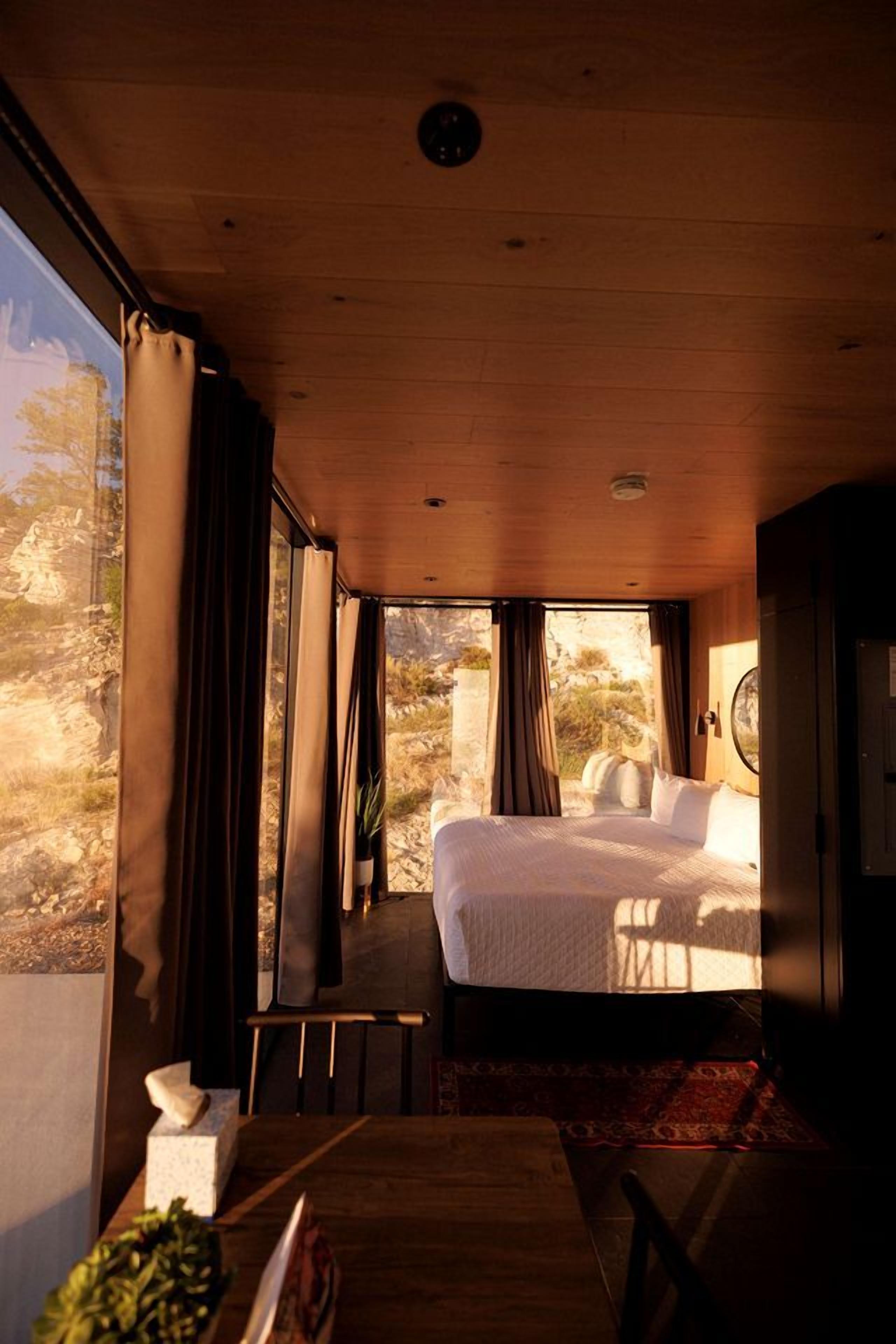 Una habitación con cama, una mesa y vistas al exterior.