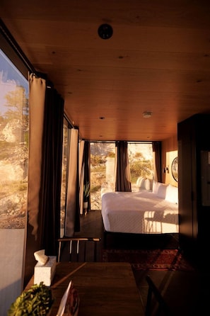 A room with a bed, a table, and a view of the outdoors. - Chic Tiny House with Outdoor Espace to Relax in Orderville, Utah (Orderville)