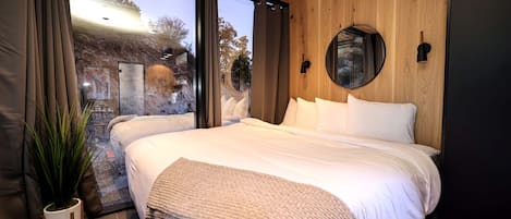 A modern bedroom with a large bed, a circular mirror, and a view of the outdoors.