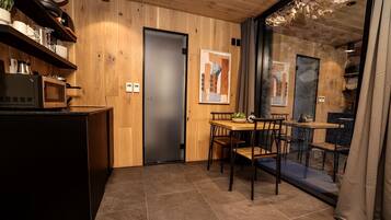 A modern kitchen with a built-in microwave, a refrigerator, and a dining area with a table and chairs.