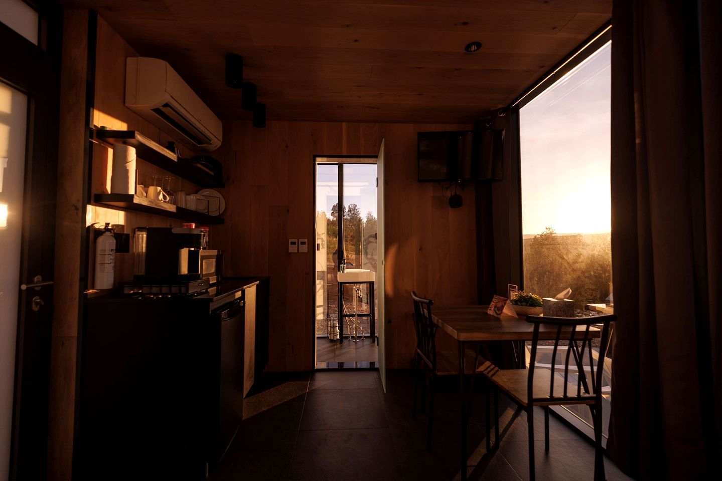 Un intérieur en bois comprenant une cuisine, un coin repas et de grandes fenêtres.