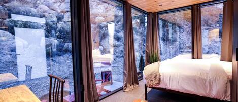 A bedroom with a bed, a wooden table, and a chair.
