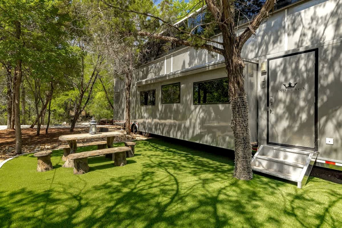 A mobile home with a covered patio area, picnic tables, and a door with a star emblem.