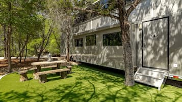A mobile home with a covered patio area, picnic tables, and a door with a star emblem.