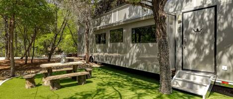 A mobile home with a covered patio area, picnic tables, and a door with a star emblem.