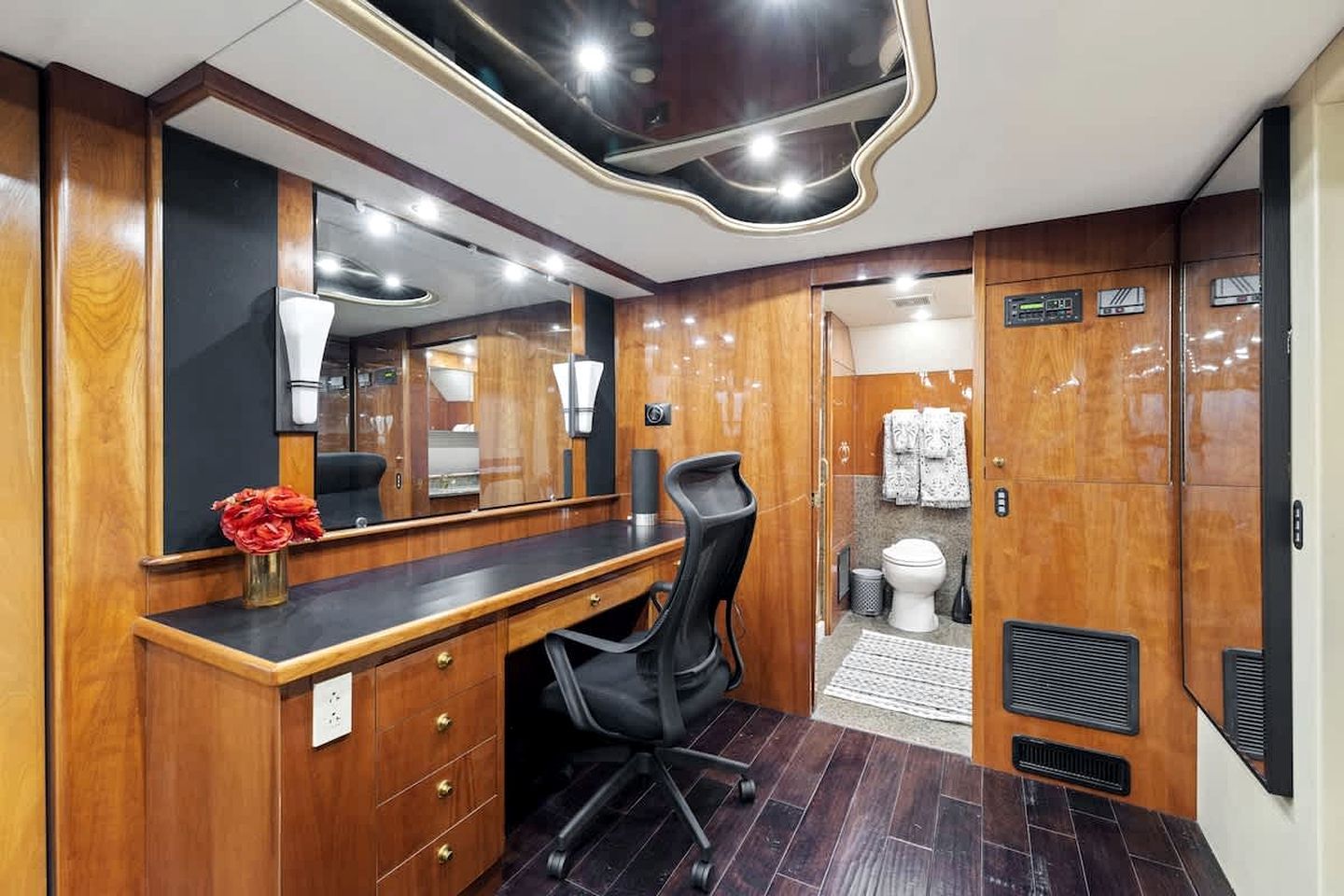 Een compacte badkamer met een houten wastafelmeubel, een spiegel, een toilet en een douche.