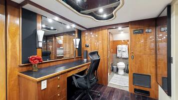 Een compacte badkamer met een houten wastafelmeubel, een spiegel, een toilet en een douche.