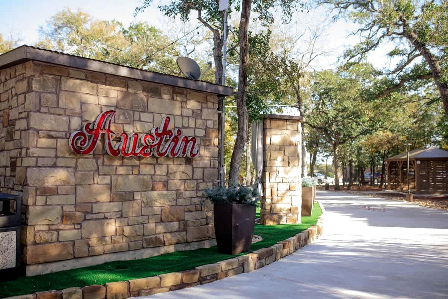 Un mur de pierre avec une enseigne indiquant « Austin », un pilier en pierre et un chemin pavé.