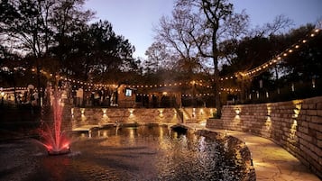 A courtyard with a water feature, stone walls, and string lights.