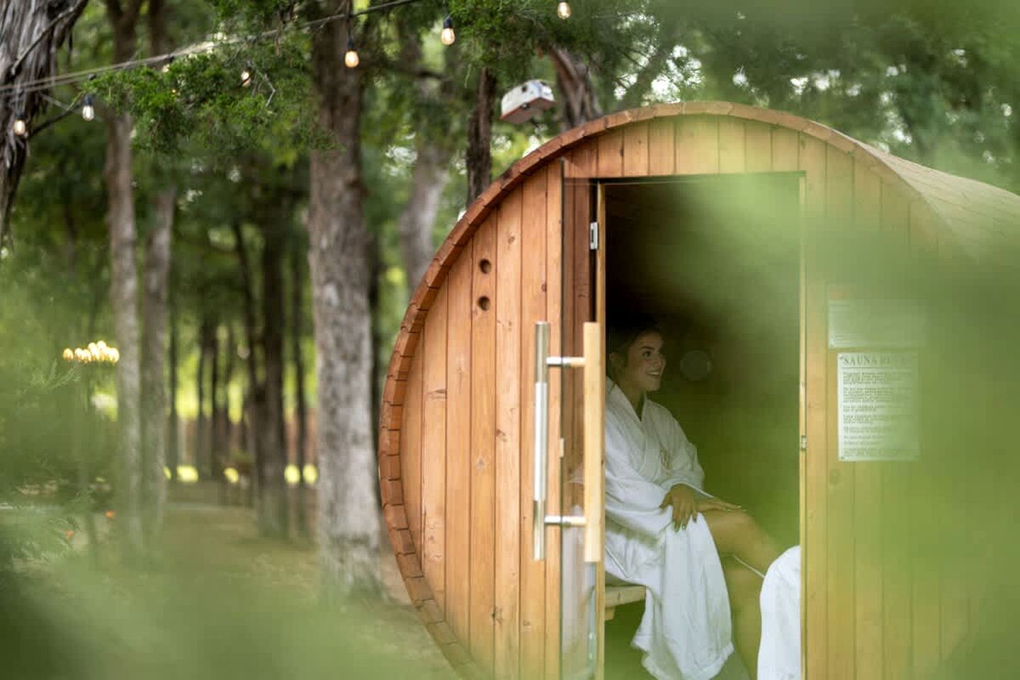Een sauna met een houten buitenkant, een deur en een bord met tekst.