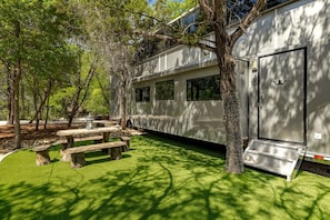 Une maison mobile dotée d’un patio couvert, d’un espace salon extérieur et d’un arbre en premier plan.