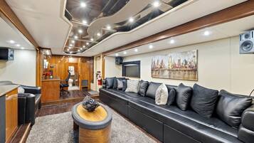 A modern living room with a black leather sofa, a wooden coffee table, and a cityscape painting on the wall.