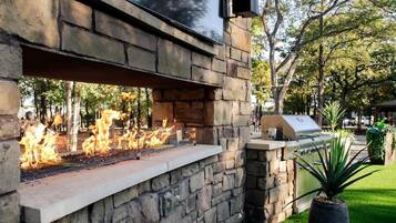 An outdoor stone wall with a built-in fire feature and a grill.