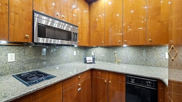 A kitchen with wooden cabinets, a stainless steel microwave, a granite countertop, and a dishwasher.