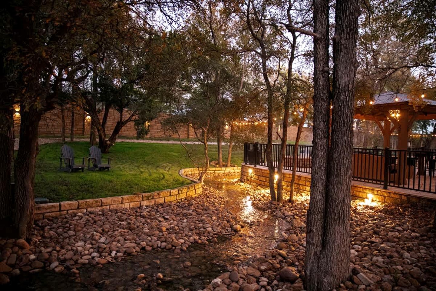 A landscaped outdoor area with a stone pathway, seating, and a gazebo.
