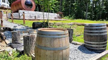A rustic outdoor setting with wooden barrels, a swing, and a stone wall.