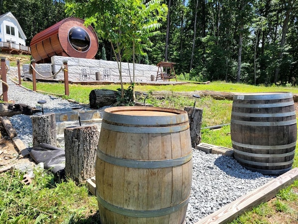 A rustic outdoor setting with wooden barrels, a swing, and a stone wall.