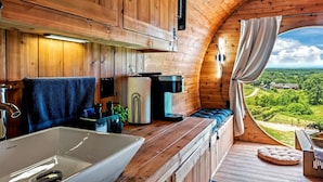 Ein gemütliches Blockhaus mit Holzinnenausbau, einem großen Fenster, einem Waschbecken und einer behaglichen Sitzecke.