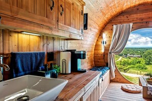 A cozy cabin with a wooden interior, a large window, a sink, and a cozy seating area.