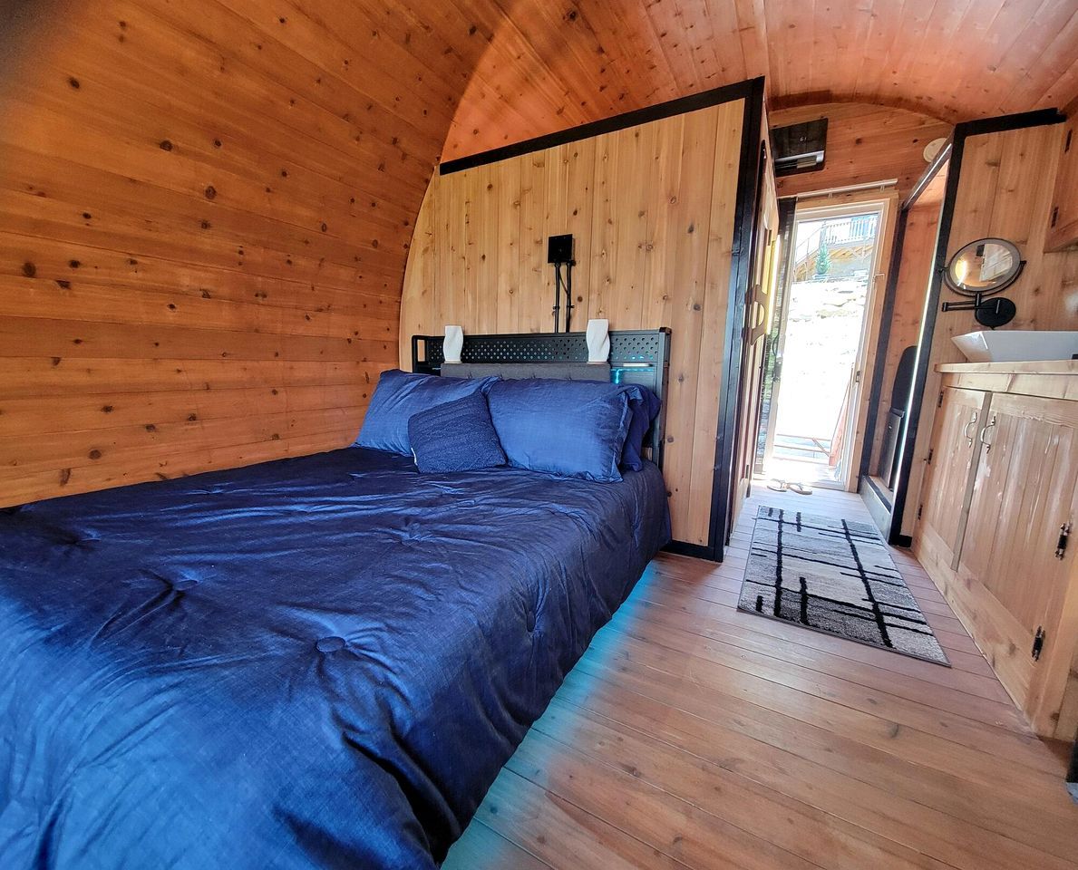 A bedroom with a bed, wooden walls, a window, and a door.