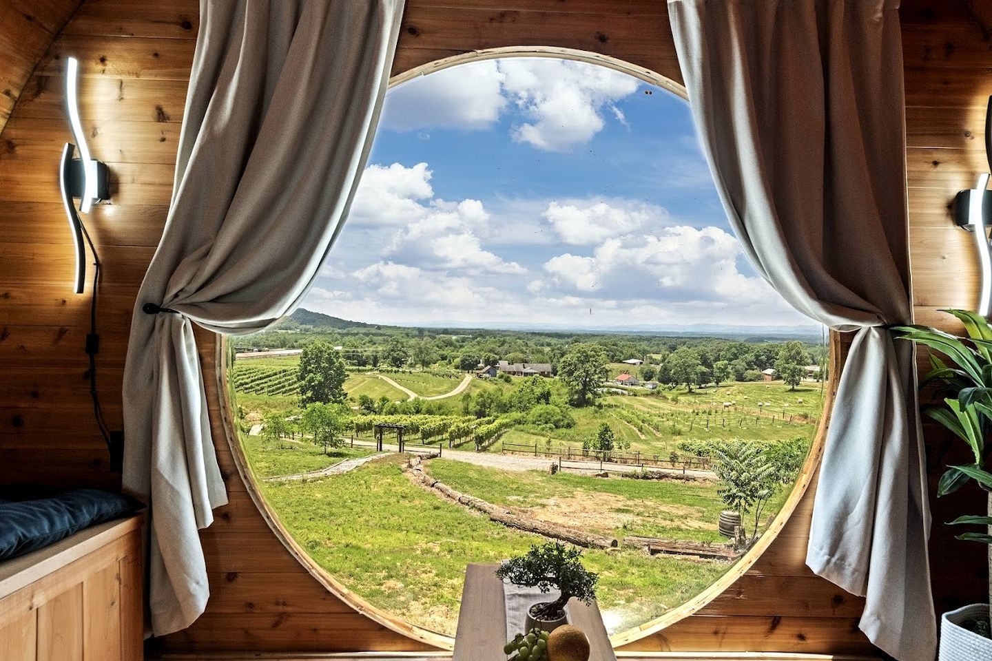 Une pièce dotée d’une grande fenêtre circulaire, de murs en bois et de rideaux.