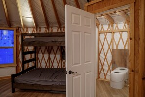 A room with a bunk bed, a wooden door, a window with a view, and a toilet. - Wonderful Yurt with Sauna and Incredible Mountain Views in Boise, Idaho (Boise)