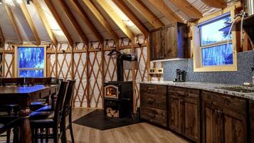 Une cuisine rustique avec un poêle à bois, des armoires en bois et un coin repas comprenant une table et des chaises.
