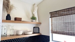 A kitchen with wooden shelves, a black and white tiled backsplash, and a window with blinds. - Family Friendly Cabin with BBQ in Glendale, Utah (Glendale)