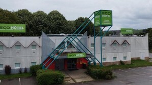 Un edificio con varios letreros que indican “ECO HOTEL” y “ROUEN - LOUVIERS - LE VAUDEUIL”.