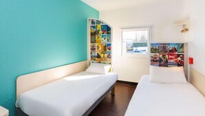 Habitación de hotel con dos camas individuales, ventana con vistas y pared decorada con carteles de viajes.