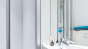Un baño moderno con lavamanos blanco, grifo cromado y cabina de ducha de vidrio.