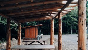 Een rustieke houten constructie met een picknicktafel en een klein huisje.