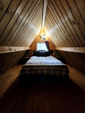A small, cozy attic bedroom with a single bed, wooden walls, and a sloped ceiling. - Fantastic Cabin Next to Wonderful Hiking Trails in Seward, Alaska (Seward)
