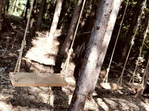 A wooden swing suspended by ropes in a forested area. - Eco Friendly Safari Tent with a Creek View in Forks, Washington, near the Hoh Rainforest (Forks)