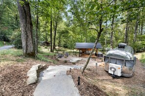 Un rustico chalet con una zona salotto esterna coperta, un vialetto in pietra che conduce all'ingresso e un camper d'epoca nelle vicinanze.