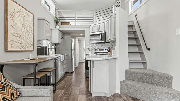 A compact kitchen with white cabinetry, a dining area with a bench, and a staircase. - Beautiful Cabin with Fire Pit and Barbecue in Fredericksburg, Texas (Fredericksburg)