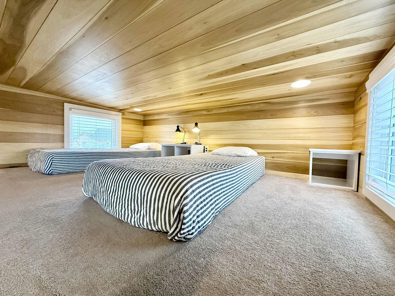 A room with a bed, a bedside table, a lamp, and a window.