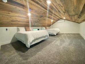 A bedroom with two beds, a wooden ceiling, and carpeted floor. - Spacious Cozy Cabin with Back Porch in Livingston, Texas (Livingston)
