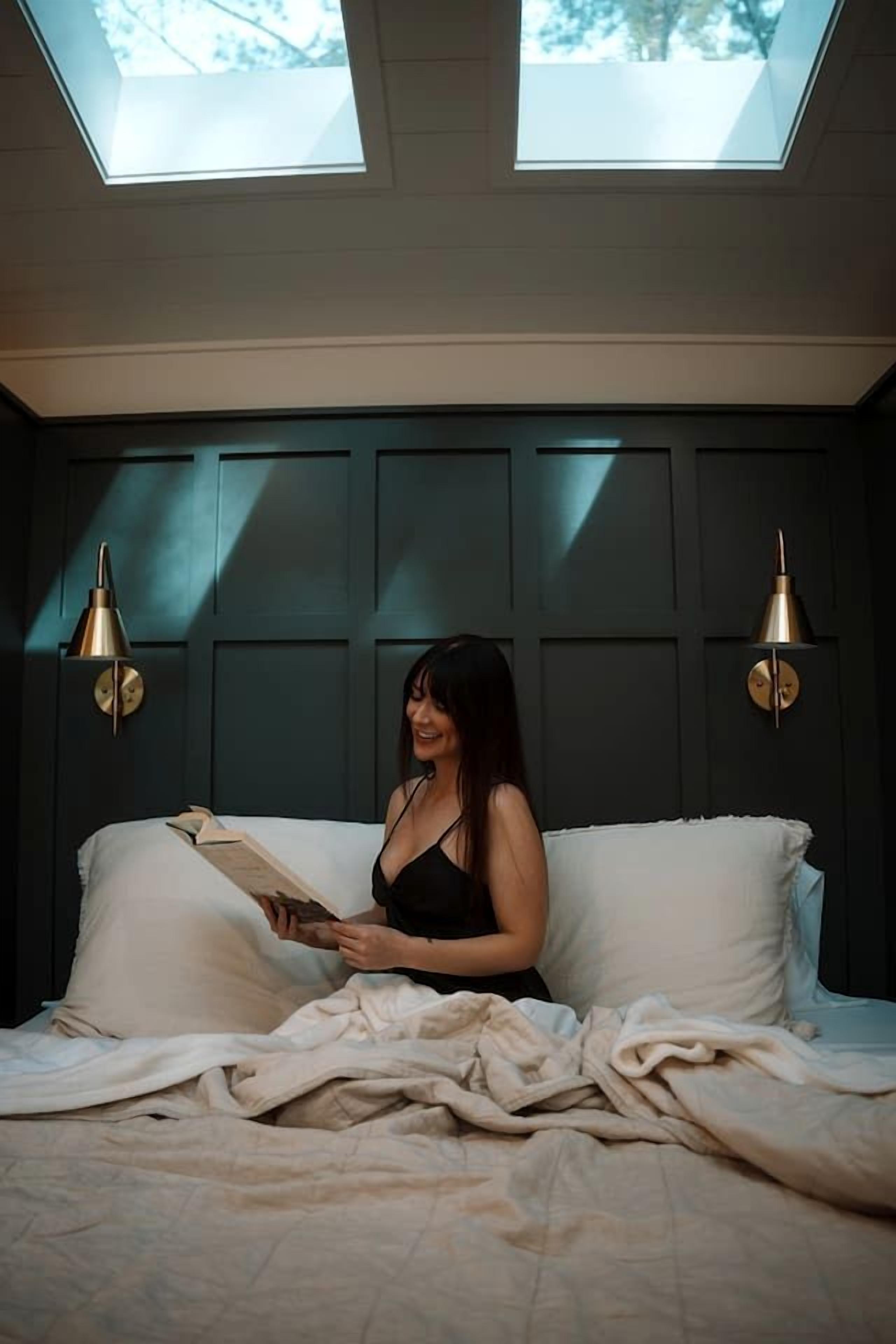 Une chambre avec un lit, deux lampes fixées au mur et une lucarne.