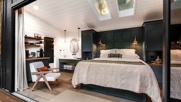 A bedroom with a bed, bedside tables, a mirror, and a window with a view.
