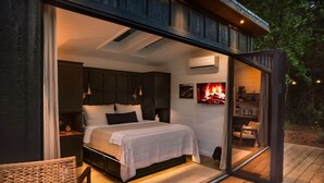 Un dormitorio con cama, mesitas de noche y televisión.