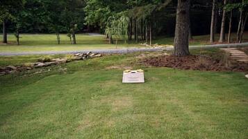 A wooden bench with a table in a grassy outdoor area.