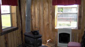 A rustic room with a wood-paneled interior, a black stove, a white radiator, and a red chair.