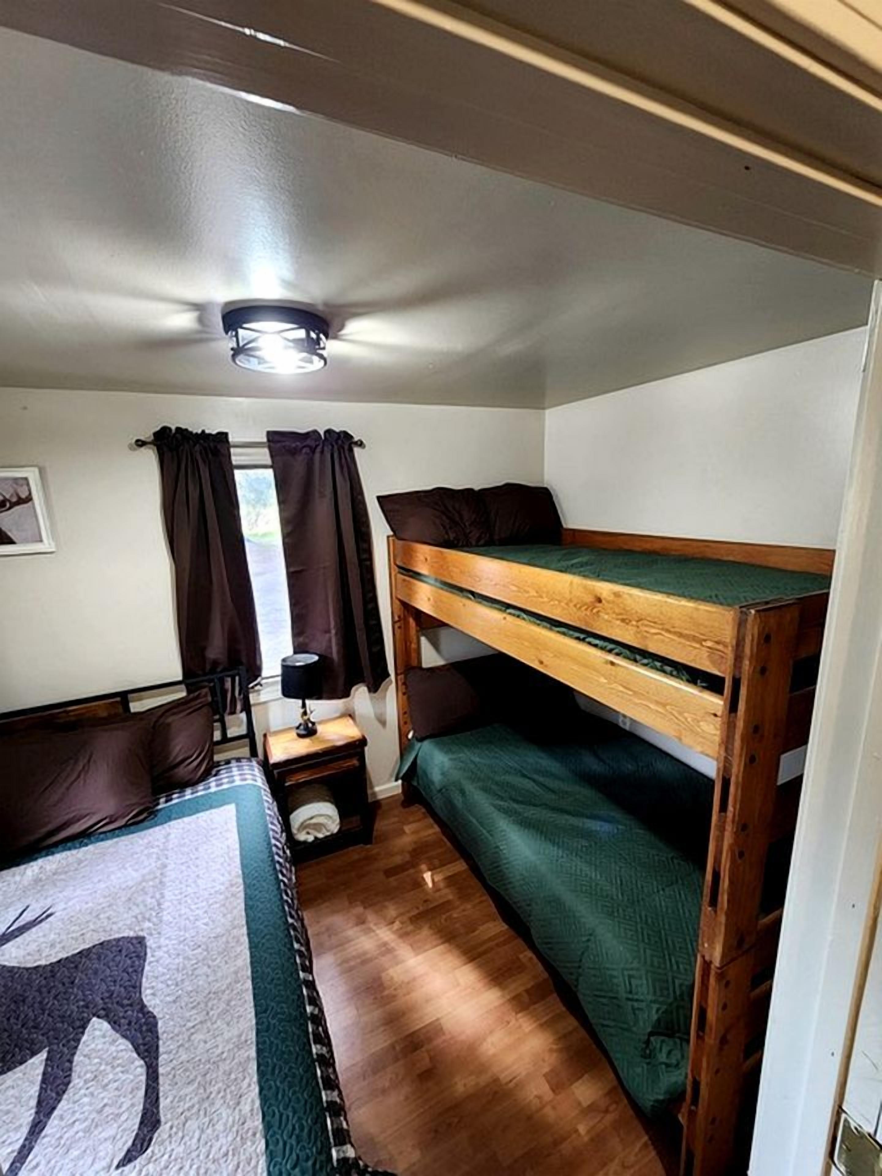 A bunk bed room with a wooden headboard, a nightstand with a lamp, and a rug with a deer design.