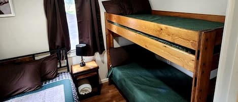 A bunk bed room with a wooden headboard, a nightstand with a lamp, and a rug with a deer design.
